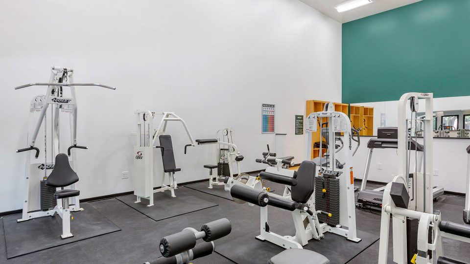a gym room with equipment and mirrors at The Breck