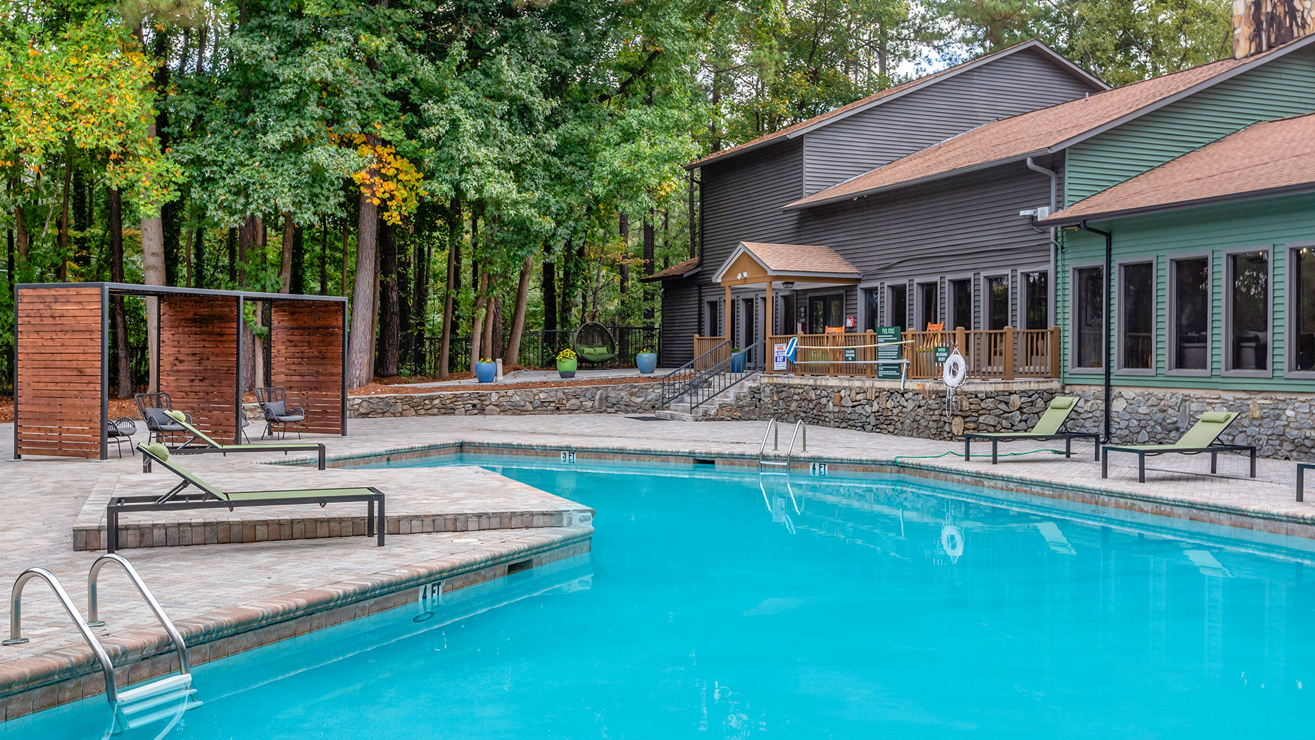 a pool in the woods with lounge chairs and a fire pit at The  Breck