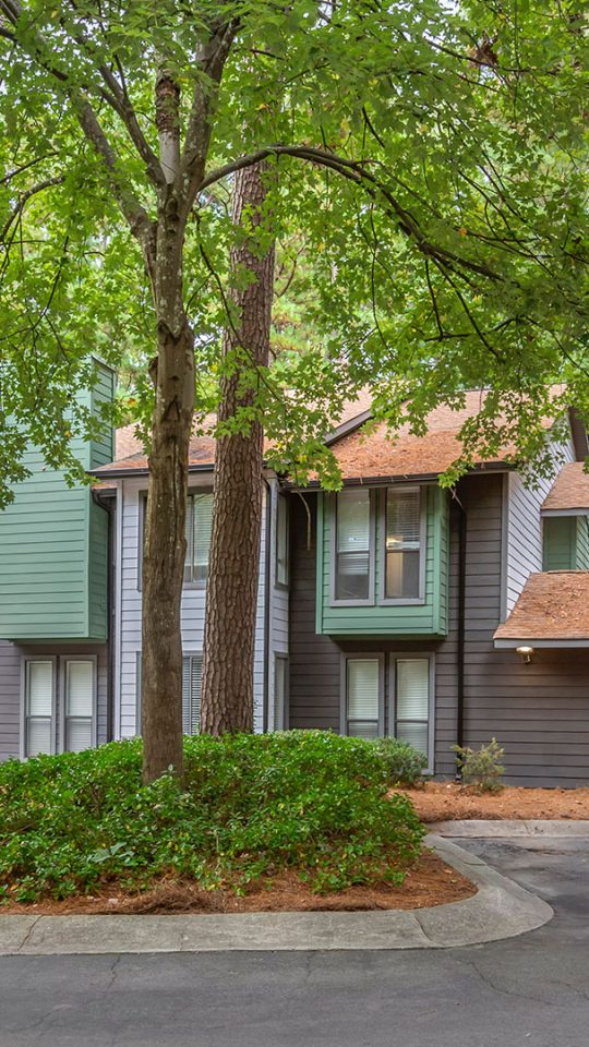 the exterior of an apartment complex with trees and bushes at The  Breck